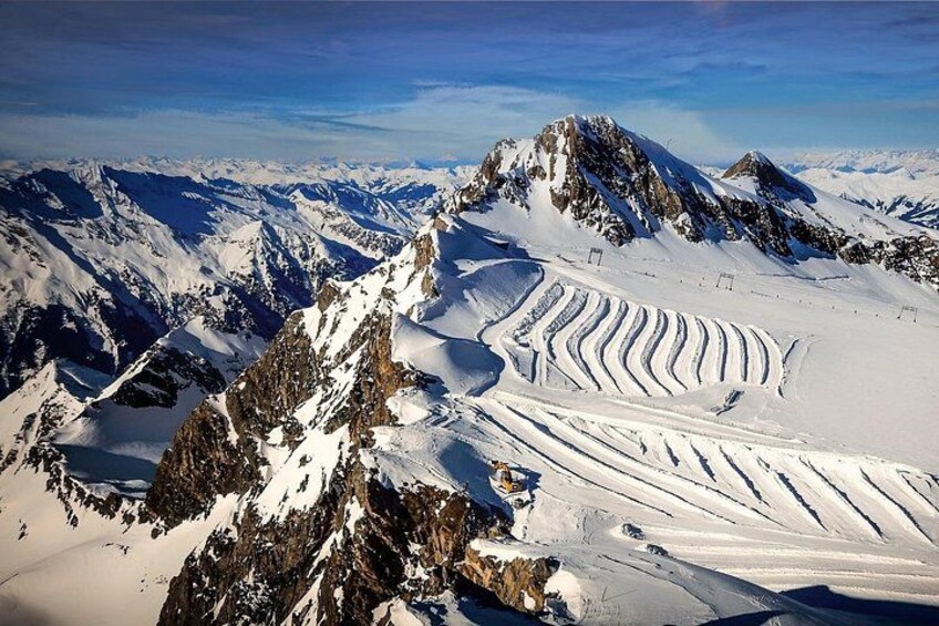 A snow-covered mountain range with distinct ski tracks. 1