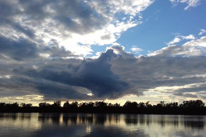 A lake with a cloudy sky and a silhouette of trees in the background. 5