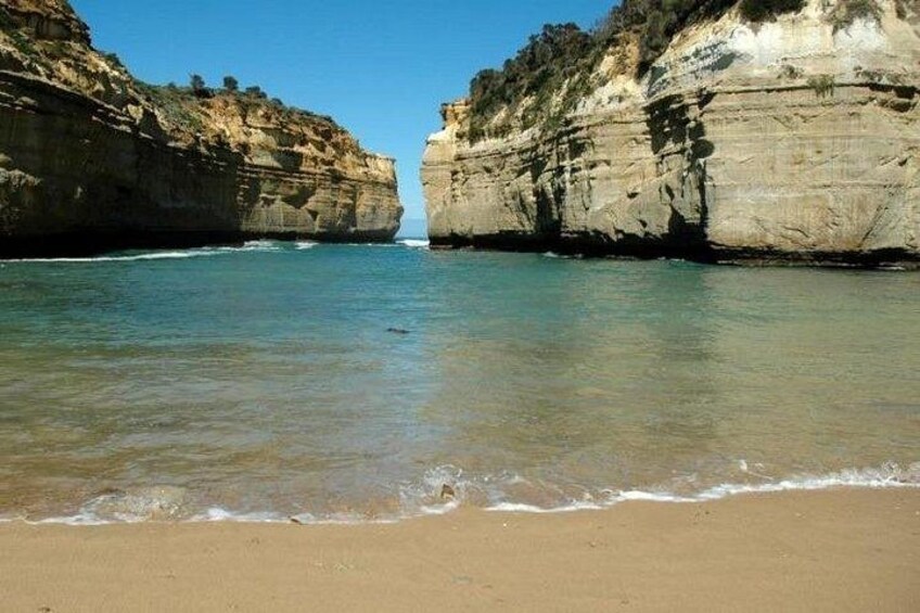 A beach with clear water, sandy shore, and rocky cliffs. 5