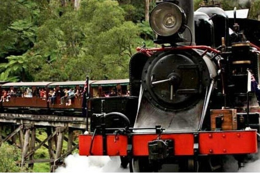 A steam locomotive with passengers on a bridge. 2