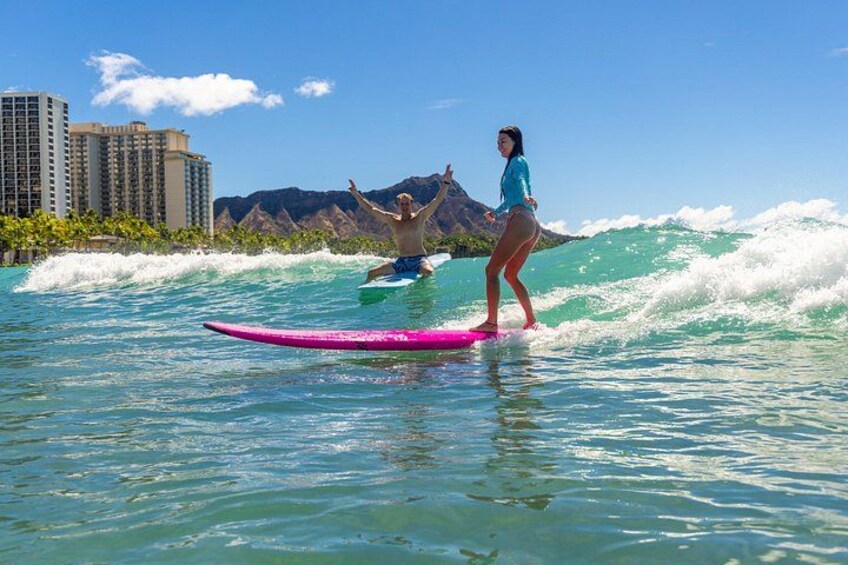 A person surfing on a pink board with a cityscape and mountains in the background. 5