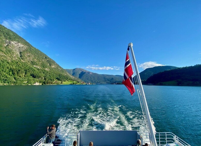 A boat on a lake with a flag, mountains, and greenery. 4