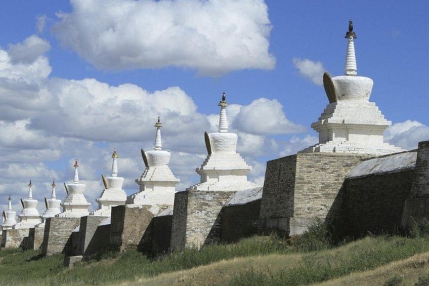 A row of white stupas with black bases, set against a clear blue sky. 5