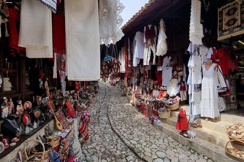 A cobblestone street with shops selling textiles and crafts. 5