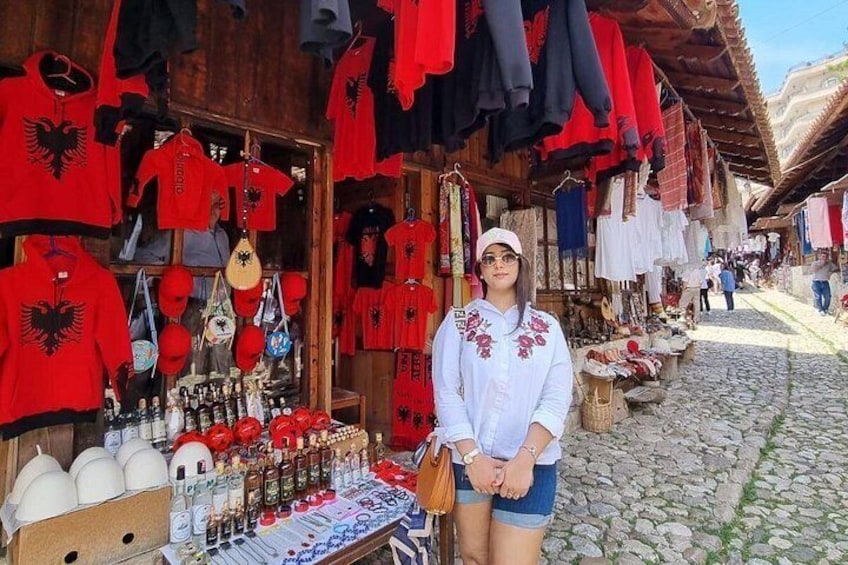 A person standing in front of a market stall with various items on display. 1