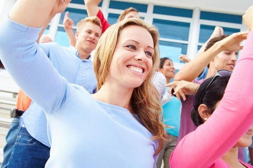 A group of people outdoors, some raising their hands, possibly in a celebration or gathering. 1