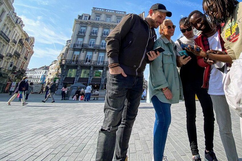 A group of people standing on a paved square with buildings in the background. 4