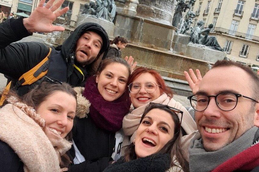 Eine Gruppe von Personen macht ein Selfie vor einem Brunnen mit Statuen. 4
