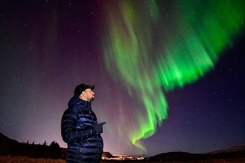 Una persona parada bajo un cielo nocturno con la aurora boreal. 2