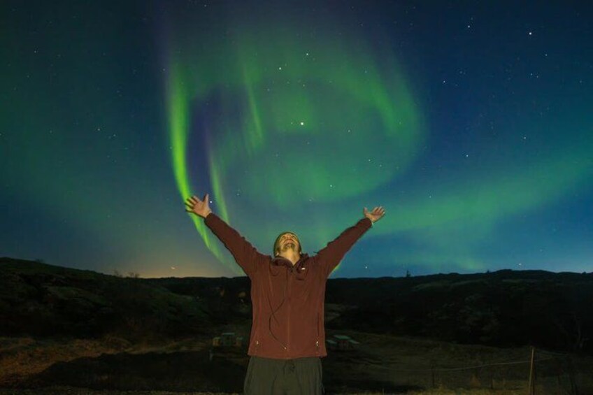 Una persona con los brazos levantados bajo la aurora boreal. 4