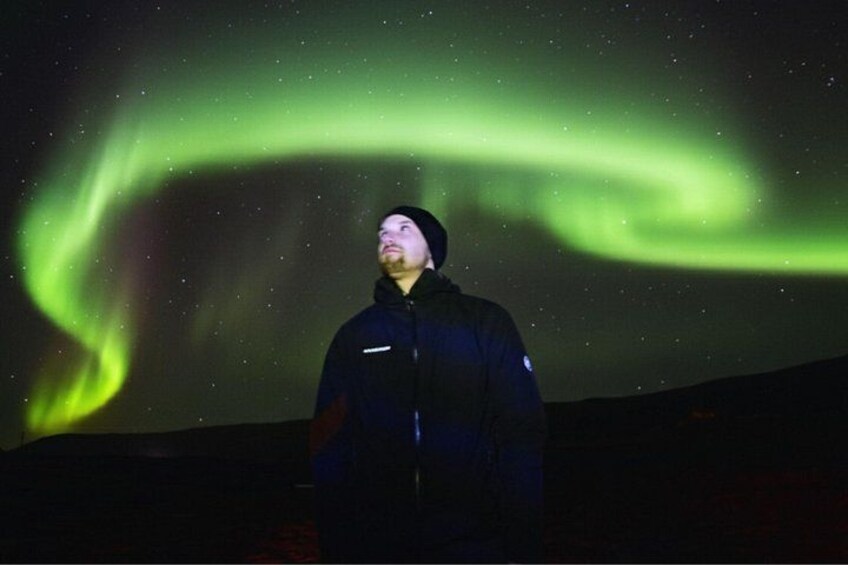 Una persona bajo una exhibición de aurora verde. 2