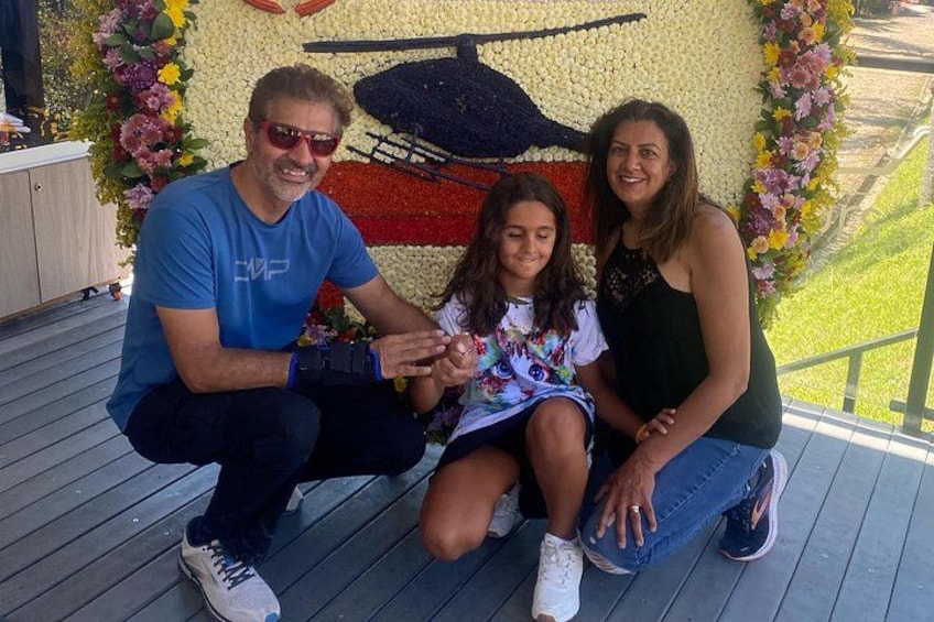 Three people sitting on a wooden deck with a floral backdrop. 4