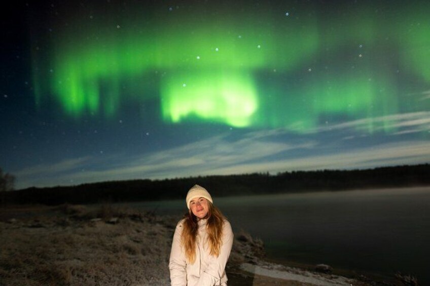 Una persona de pie junto a un lago, con la aurora boreal al fondo. 4