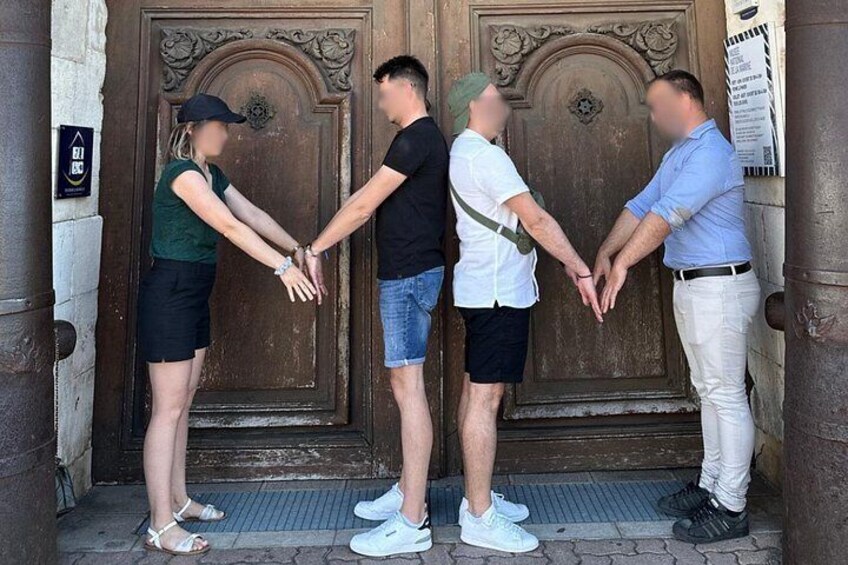 Cuatro personas tomadas de las manos frente a una puerta de madera grande. 5