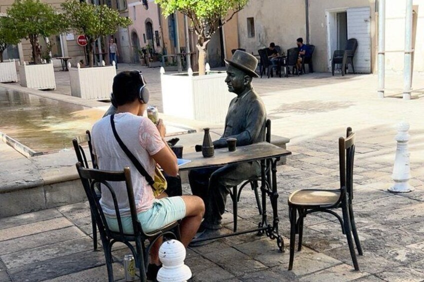 Una persona sentada a una mesa con una estatua de un hombre con sombrero. 4