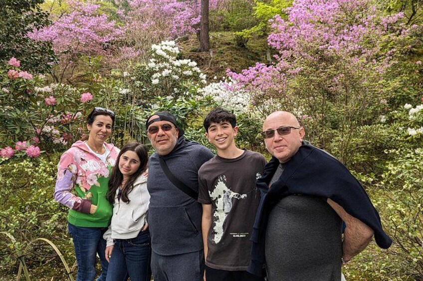 A group of people standing in a garden with blooming pink and white flowers. 5