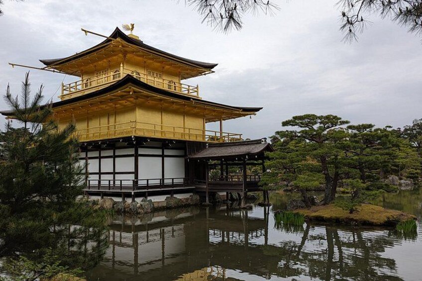 A traditional Japanese building with a golden roof, surrounded by water and pine trees. 2