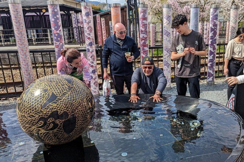 A group of people around a large decorative water feature with a patterned sphere. 4