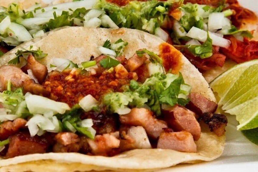 A taco with meat, lettuce, and a lime wedge. 2