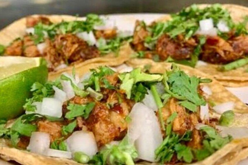Tacos with meat, onions, cilantro, and a lime wedge. 3