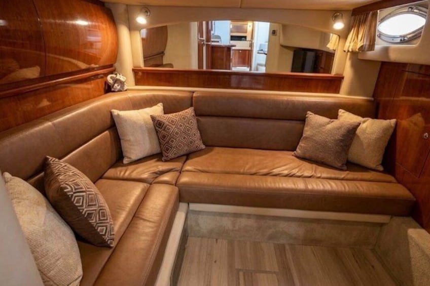 A boat interior with a leather sofa, cushions, and a wooden cabinet. 3