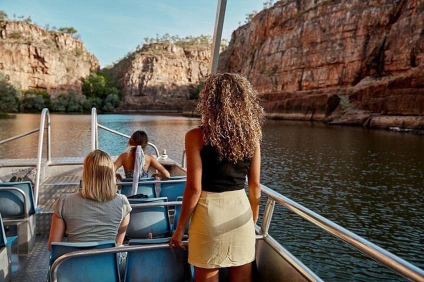 A boat with people on a calm river surrounded by rocky cliffs. 3