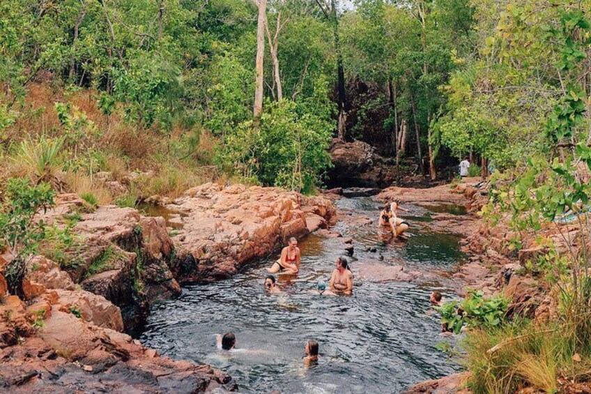 A group of people swimming in a natural water body surrounded by rocks and greenery. 4