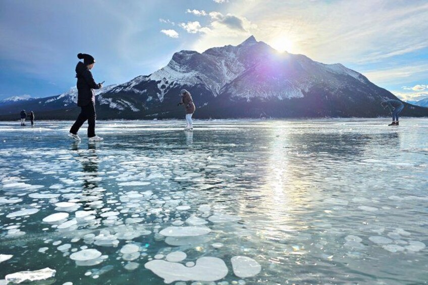 A frozen lake with people walking on the ice, a mountain in the background, and the sun shining. 5