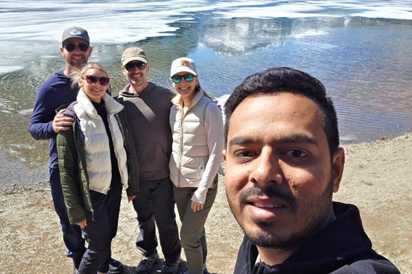 A group of people standing by a body of water with ice formations in the background. 3