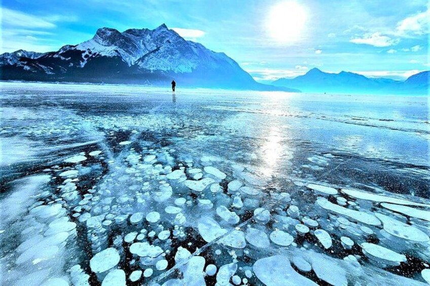 A frozen lake with ice floes and a person standing in the distance. 1