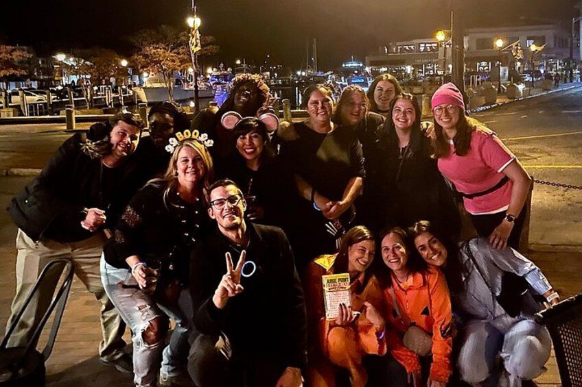 A group of people posing for a photo on a sidewalk at night. 2
