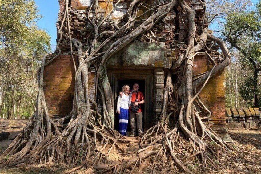 Une structure dont les racines des arbres sont très apparentes, avec deux personnes debout devant et un banc sur la droite. 3