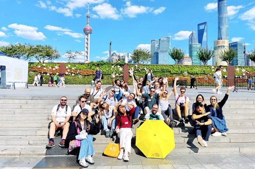 A group of people posing in an urban setting with modern buildings and a tower in the background. 2