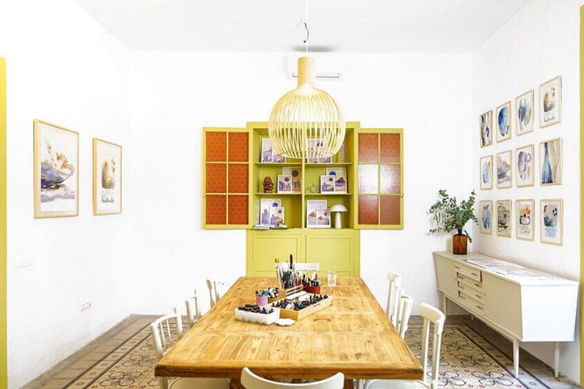 A dining room with a wooden table, chairs, a green bookshelf, and framed artwork on the walls. 2