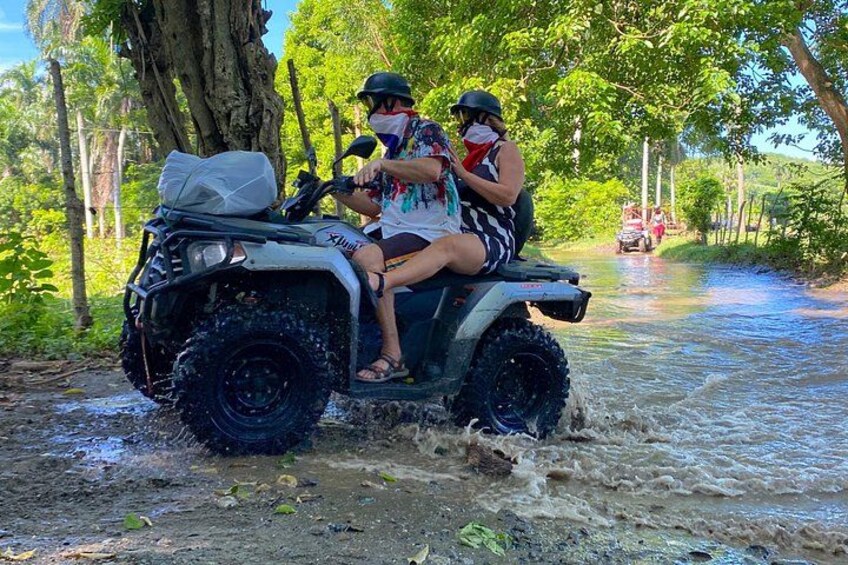 An ATV navigating a flooded rural road with passengers. 4