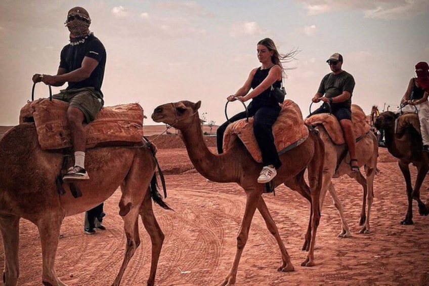 A group of people riding camels in a desert landscape. 5