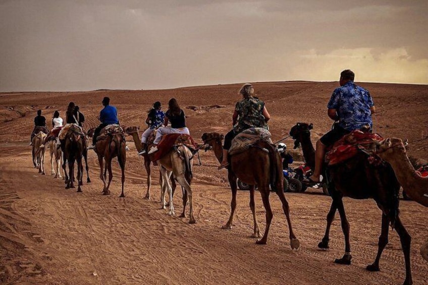 A group of people riding camels in a desert landscape. 4
