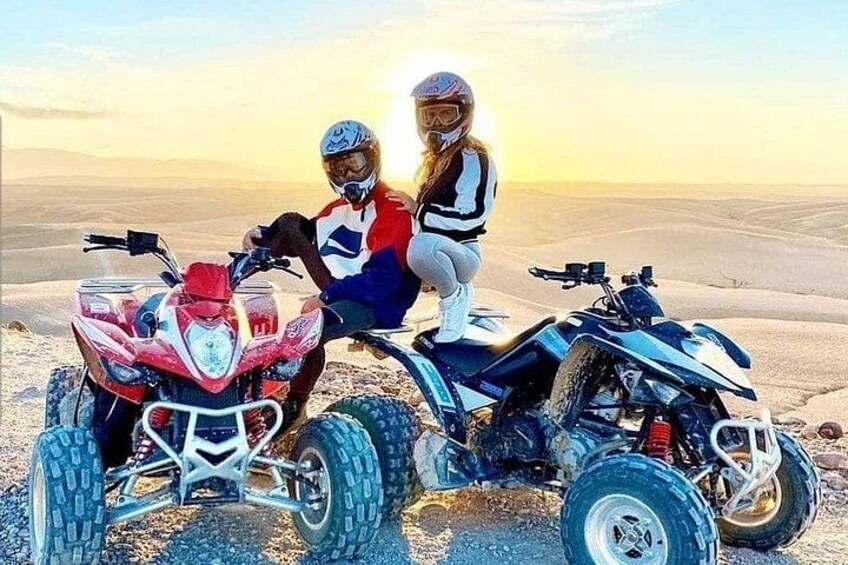 Two people on quad bikes in a desert landscape. 1