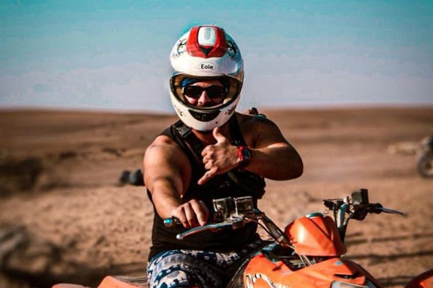A person on an orange quad bike in a desert landscape. 4
