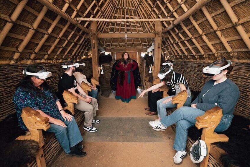 People seated in a thatched-roof structure, wearing VR headsets. 2