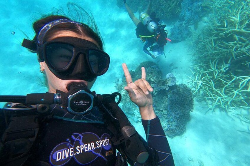 A diver underwater with a snorkel and scuba gear, making a peace sign. 1