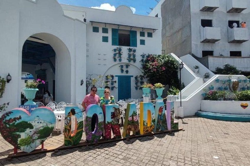 A colorful train with a heart-shaped front, a white building with blue accents, and a staircase leading to a balcony. 3