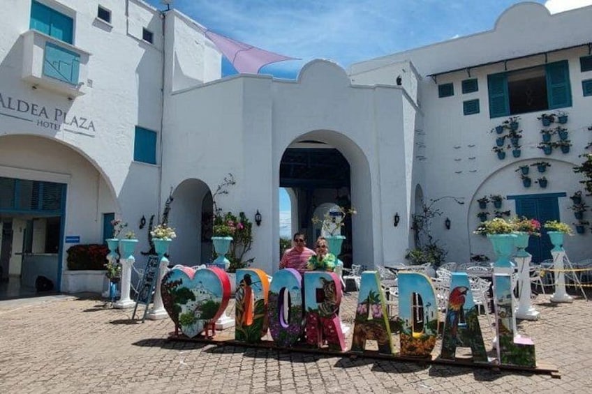 A white building with arches and a sign that reads 'ALDEA PLAZA HOTEL'. 2
