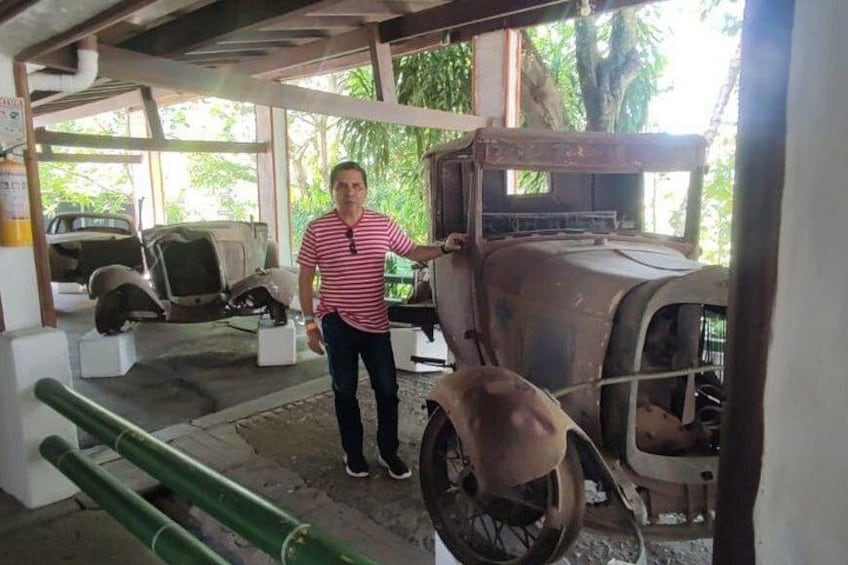 A man standing next to a vintage car in a museum. 4