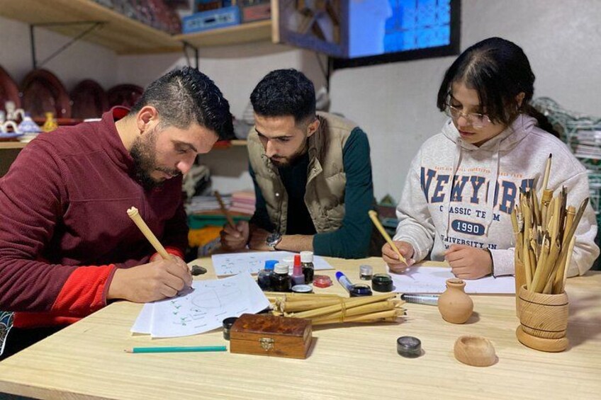 Tres personas trabajando alfarería, con herramientas y arcilla sobre una mesa. 1