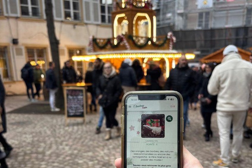 A person holding a smartphone with a Christmas market scene in the background. 5