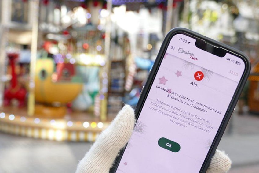 A smartphone displaying a Christmas tour app with a carousel in the background. 4