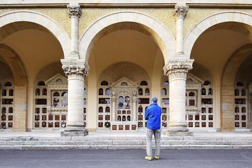 Ein Mann steht vor einem Gebäude mit Rundbogenfenstern und Säulen. 4