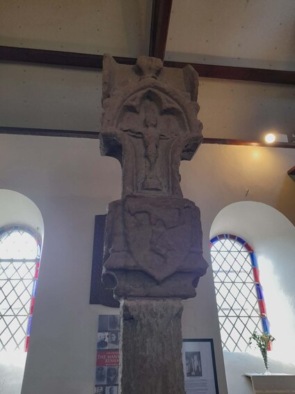 A stone sculpture of a religious figure on a pillar in a building with arched windows. 5