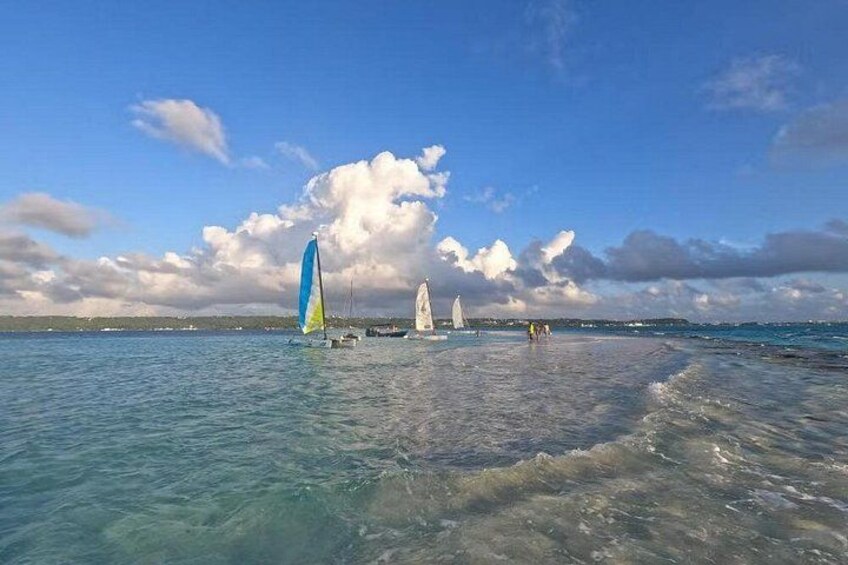 A beach with clear water, sailboats, and a partly cloudy sky. 3